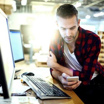 Udvid din virksomhed mod digital transformation man sitting in front of a laptop checking his phone