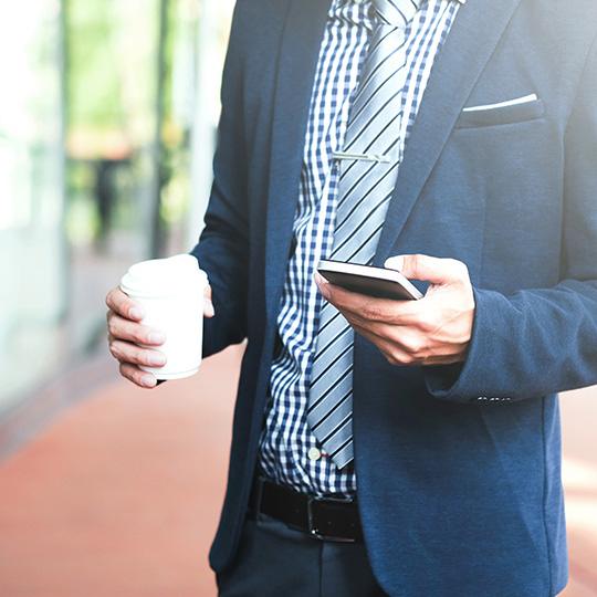 Hvorfor udskrivning stadig er essentiel businessman holding a coffee and mobile phone