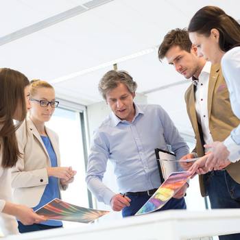 Kun toner colleagues discussing coloured printouts